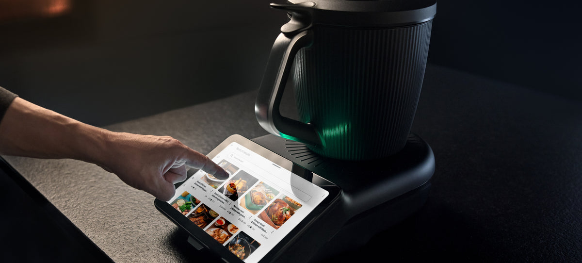 Cookidoo recipe app on a phone next to a Thermomix TM7 on the counter